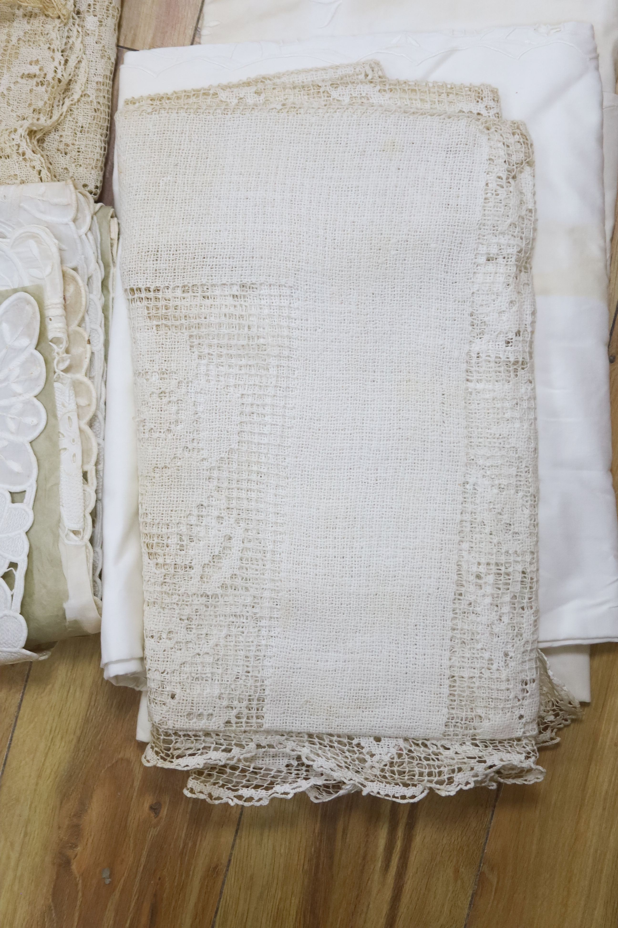 A collection of crochet edged linen tablecloths, a filet cloth and a 225cm long ornately cutworked cloth.